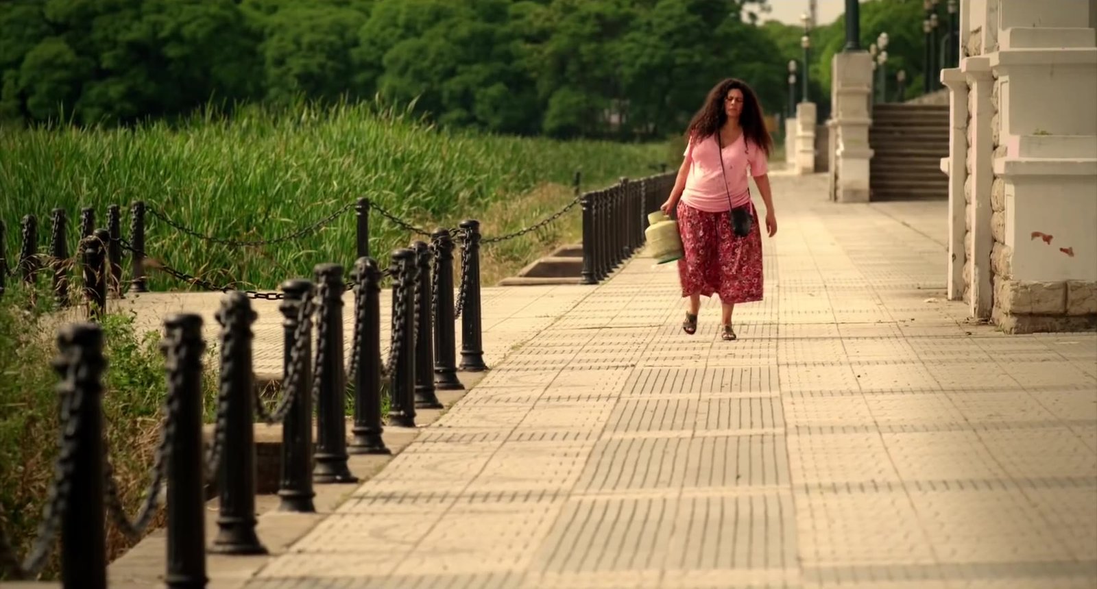 The widow walks alone along a riverside promenade